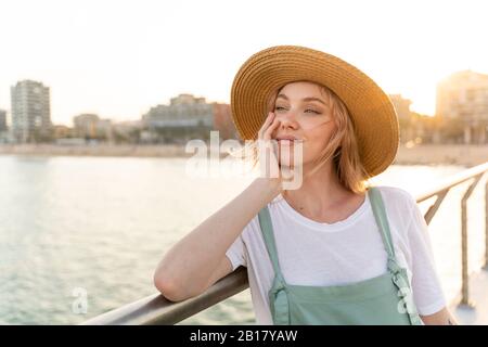 Junge Frau, die einen Tag am Meer verbringt, auf der Brücke steht Stockfoto