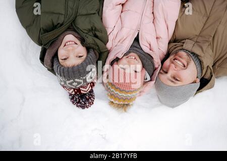 Familienporträt von Vater und zwei Kindern, die auf Schnee liegen Stockfoto