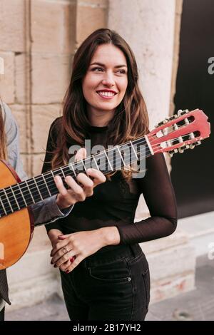 Porträt einer lächelnden jungen Frau mit Mann Gitarre in der Stadt Stockfoto