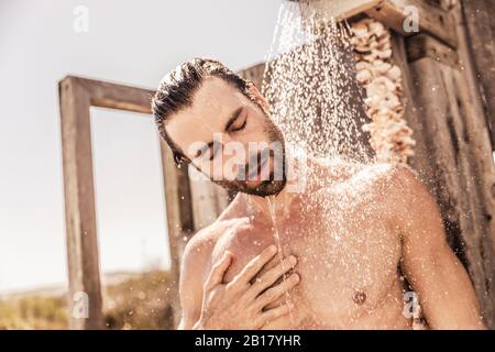 Junger Mann unter einer Dusche im Freien Stockfoto