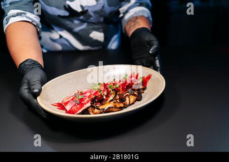 Der Koch zeigt ein zubereitetes Gericht auf dem Tisch in der Restaurantküche Stockfoto