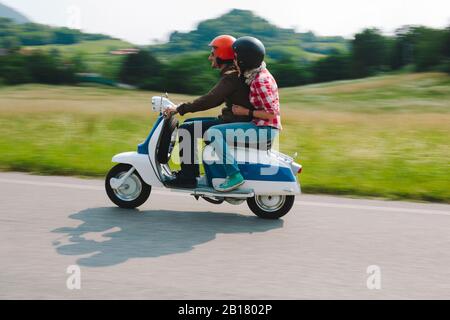 Paar reiten Vintage Motorroller auf Landstraße, Toskana, Italien Stockfoto