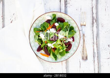 Teller mit Maissalat mit gerösteten Karotten, Rote Bete, rote Zwiebeln und Ziegenkäse Stockfoto