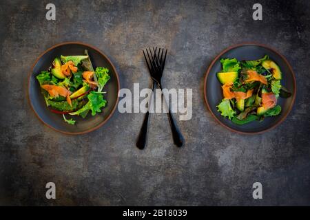 Teller mit grünem Salat mit Maissalat, Rucola, Spinat, rotem Blattsalat, Rote-Bete-Blätter, Avocado, Lachsfleisch und Balsamico-Essig Stockfoto