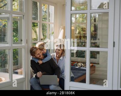 Familie mit Laptop und Kreditkarte im Wohnzimmer zu Hause Stockfoto