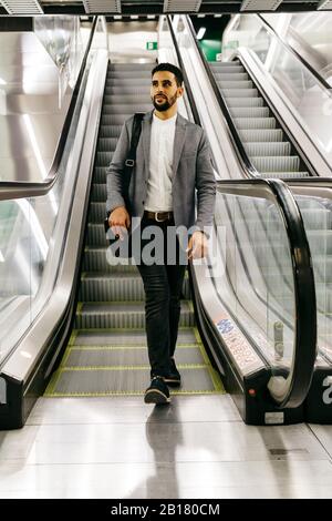 Legerer junger Geschäftsmann auf Rolltreppe Stockfoto