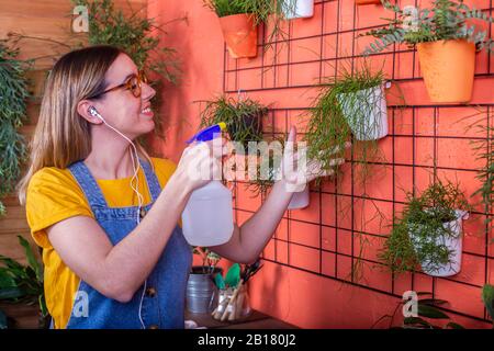 Frau sprüht auf ihrer Terrasse Wasser auf Rhipsalis Stockfoto