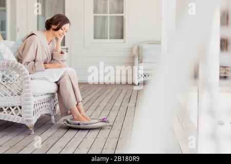 Frau mit einem Fußbad auf einer Veranda Stockfoto