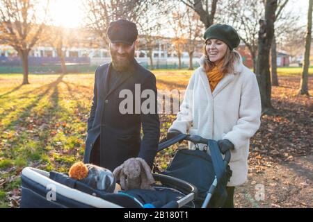 Glückliches Paar mit kleinem Sohn in einem Kinderwagen im Park Stockfoto