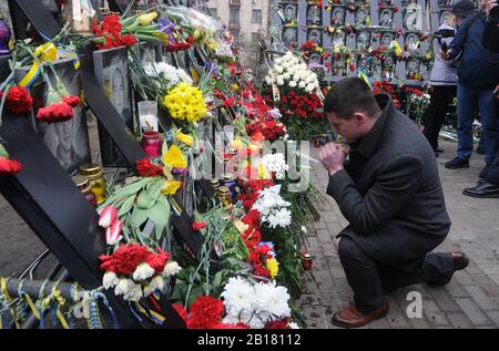 Kiew, Ukraine. Februar 2020. Ein Mann betet das Denkmal der EuroMaidan-Aktivisten oder "Helden der himmlischen Hundert", die während der Anti-Regierungs-Proteste von 2014 in der Innenstadt von Kiew getötet wurden.die Ukrainer markieren den 6. Jahrestag der Maidan-Revolution oder Euromaidan-Revolution, bei der mindestens 100 Demonstranten getötet wurden. Credit: Sopa Images Limited/Alamy Live News Stockfoto