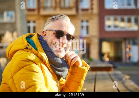 Porträt eines lächelnden, reifen Mannes, der in der Stadt eine Sonnenbrille trägt Stockfoto