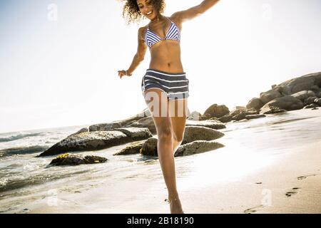 Glückliche junge Frau, die Spaß am Strand hat Stockfoto