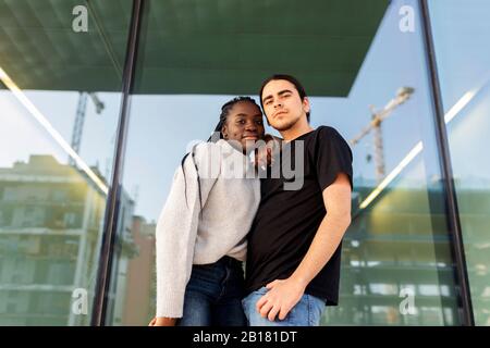 Porträt eines selbstbewussten jungen Paares, das an einer Glasfront steht Stockfoto