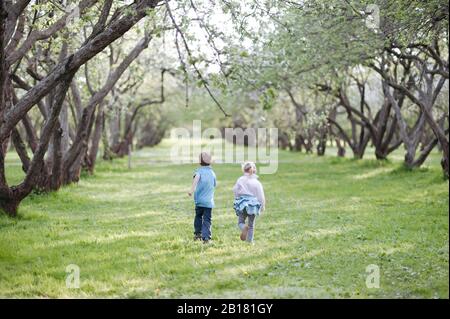 Rückblick auf kleine Junge und Mädchen, die nebeneinander auf einer Wiese laufen Stockfoto