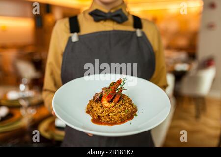 Kellnerin, die Paella auf weißem Teller serviert Stockfoto