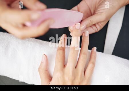 Nahaufnahme von Manikuristen, die Nägel von weiblichen Klienten anheften, selektiver Fokus Stockfoto
