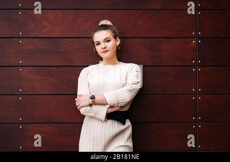 Porträt einer jungen Frau, die an einer Holzwand steht Stockfoto