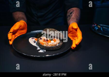 Nahaufnahme des Küchenchefs, der ein Burger-Gericht in der Restaurantküche präsentiert Stockfoto
