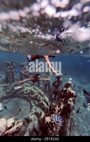 Frau ein Mann, der in der Nähe von Unterwasserskulpturen von Jason deCaires Taylor, Gili Meno Island, Bali, Indonesien, schwimmt Stockfoto