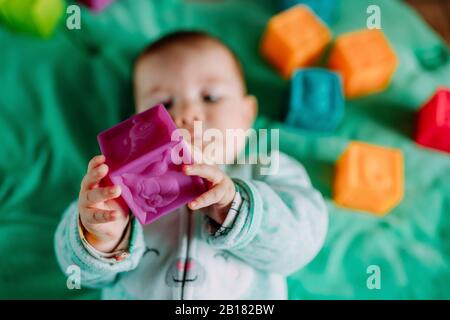 Baby Hände halten lila Gummi Würfel Spielzeug, Nahaufnahme Stockfoto