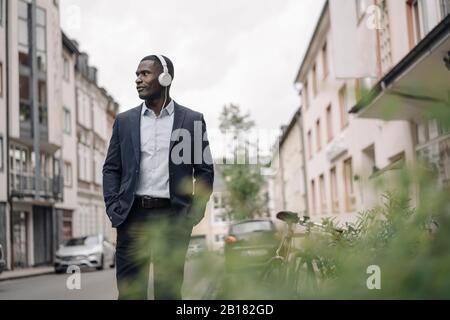 Junge Geschäftsleute hören Musik mit Kopfhörern, die auf der Straße laufen Stockfoto