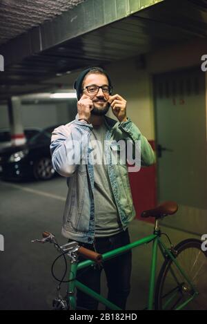 Junger Mann steht im Parkhaus mit seinem Fixie-Fahrrad Stockfoto