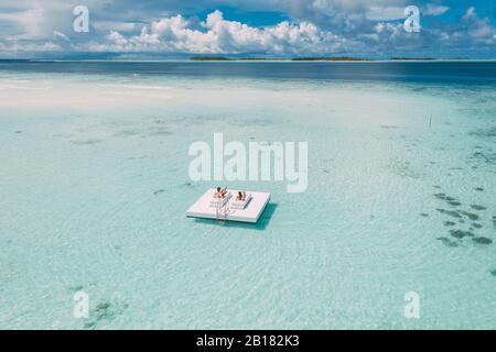 Paar liegt auf einer Plattform im Meer, Maguhdhuvaa Island, Gaafu Dhaalu Atoll, Malediven Stockfoto