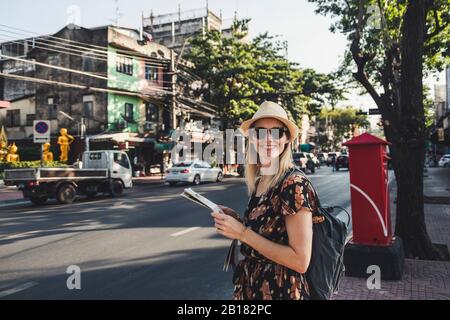 Lächelnde Frau mit Karte an einer Straße, Bangkok, Thailand Stockfoto
