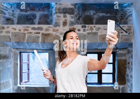 Frau, die ein selfie nimmt, während sie die Wände ihres neuen Hauses bemalt Stockfoto