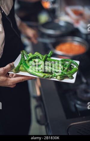 Küchenchef mit grünem Spargel in der Restaurantküche Stockfoto