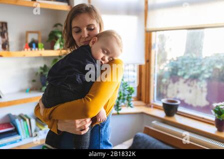 Mutter hält ihren schlafenden Sohn an der Schulter Stockfoto