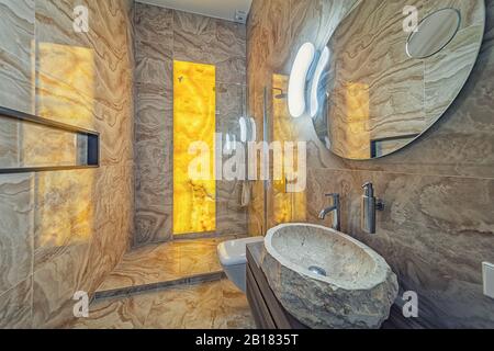 Elegantes Badezimmer in edlem natürlichen Onyx mit Waschbecken und Spiegel aus Stein Stockfoto