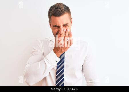 Junger, gutaussehender, eleganter Geschäftsleute über isoliertem Hintergrund, der etwas stinkigen und ekelhaften, unerträglichen Geruch riecht und mit den Fingern Atem hält Stockfoto