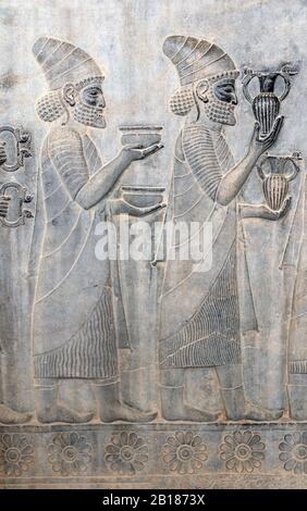 Alte Mauer mit Basreliefzug mit ausländischen Botschaftern mit Geschenken und Spenden, Persepolis, Iran. UNESCO-Weltkulturerbe Stockfoto