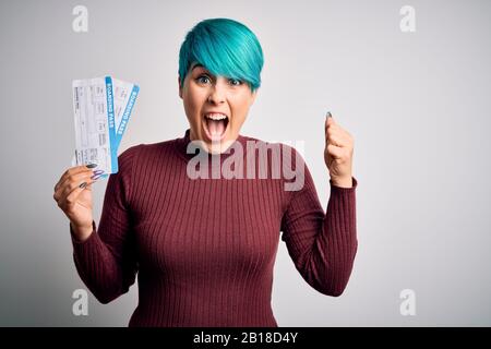 Junge Frau mit blauen Modehaaren, die Platane über isolierten Hintergrund hält und stolz schreit und Sieg und Erfolg feiert, war sehr begeistert Stockfoto