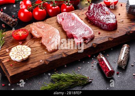 Frisches saftiges Steak aus Rindfleisch, Schweinefleisch und Huhn mit Gemüse zum Kochen bereit. Steaks aus verschiedenen Fleischsorten, die zum Kochen zubereitet werden Stockfoto