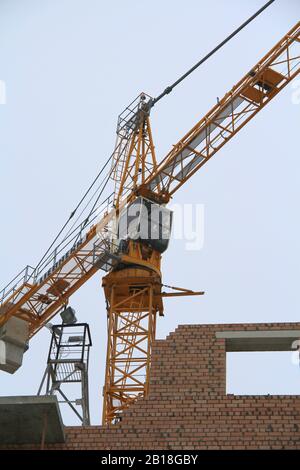 Turmkran arbeitet an einer Baustelle gegen den Himmel. Kran-Führerhaus nah. Stockfoto