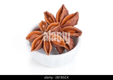 Anisstern (Illicium verum) in einer weißen Schüssel auf weißem Grund. Auch als Star Anis oder Chinese Star Anis bezeichnet. Wird als Gewürz in der Küche verwendet Stockfoto