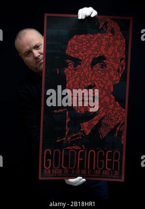 Prop Store Poster Consultant Mark Hochman hält ein Mondo Poster 2007 für den James-Bond-Film "Goldfinger" von 1964 (Schätzung £1,5k - £2,5k) während einer Vorschau für die bevorstehende Kinoposter-Auktion des Prop Store auf. Stockfoto