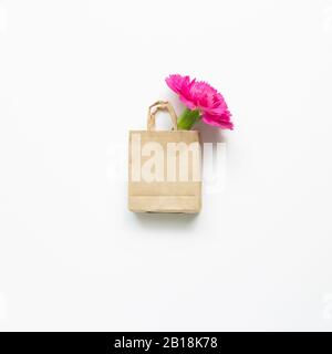 Rosa Spray Nelkenblume in Einkaufstasche auf weißem Hintergrund. Blumendesign, flacher Lay, Draufsicht, Kopierbereich Stockfoto