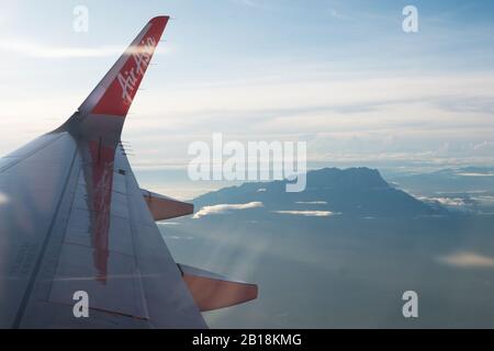 Kota KINABALU, MALAYSIA - 02. Dezember 2019: Das Logo von Air Asia, das auf dem Flügel des Flugzeugs zu sehen ist, und Mount Kinabalu im Hintergrund. Stockfoto