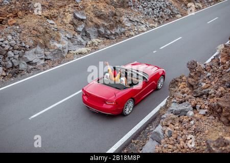 Blick auf die Landschaft auf der schönen geraden Straße im vulkanischen Tal mit einer Frau, die ein rotes Cabriolet fährt, von oben. Reisen mit dem Auto auf der Insel Tenera, Spanien Stockfoto