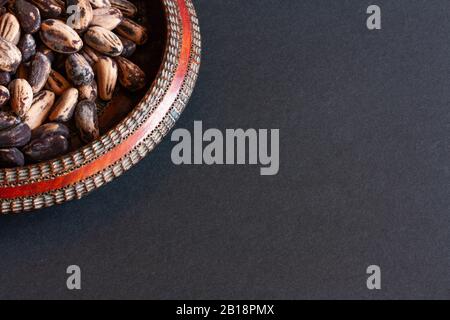 Pinienkerne auf Holzplatte mit rotem Rand auf schwarzem Grund. Stockfoto