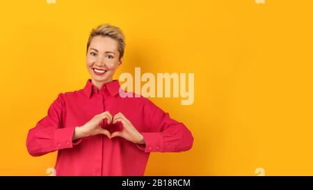 Eine schöne, entspannte, gesunde Europäische Frau hat ein schnörkeliges Lächeln, genießt einen wunderbaren Tag, drückt positive Emotionen aus, trägt ein rosafarbenes Sweatshirt Stockfoto