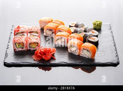 Verschiedene Arten von Sushi-Rollen auf einem Steinbrett. Stockfoto