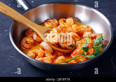 Fisch und Meeresfrüchte Garnelen Scampi mit Knoblauch-Butter-Sauce mit Petersilie, auf einem Skillet auf Betongrund, horizontale Ausrichtung, Nahaufnahme Stockfoto