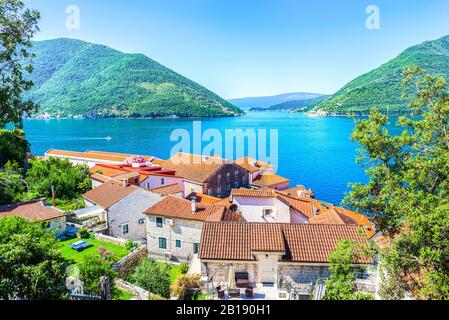 Rote Dächer der Häuser in Perast auf Meer- und Berggrund Stockfoto