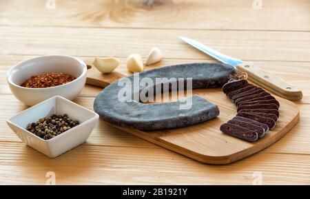 Schneiden Sie Scheiben der speziellen Pirot-Hufeisenwurst - Peglana Pirotska kobasica, aus Kalbfleisch, Schaf- und Ziegenfleisch, mit Zusatz von Knoblauch Stockfoto