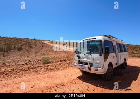 Geländewagen Toyota Coaster mit Geländewagen auf einer roten Straße im australischen Outback in der Nähe von Alice Springs, Northern Territory, NT, Australien Stockfoto