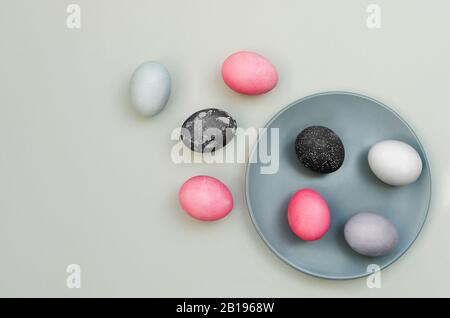 Bunte strukturierte ostereier auf blauem Teller und in dessen Nähe. Ungewöhnliche Version. Mit natürlichen Pigmenten bemalte Eier. Flaches Lay Stockfoto